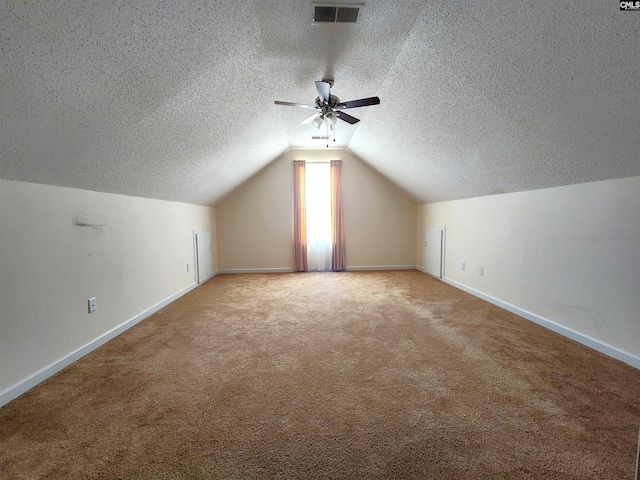 bonus room featuring ceiling fan, lofted ceiling, carpet floors, and a textured ceiling