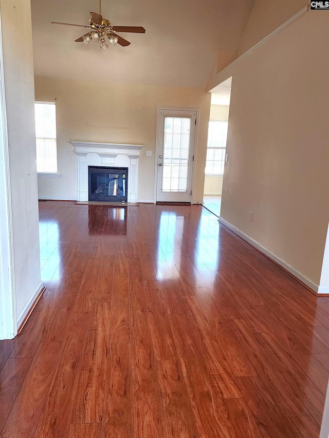 unfurnished living room with hardwood / wood-style floors, high vaulted ceiling, and ceiling fan