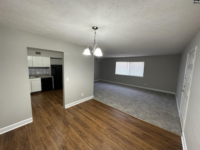 unfurnished dining area with dark carpet, a textured ceiling, and a notable chandelier