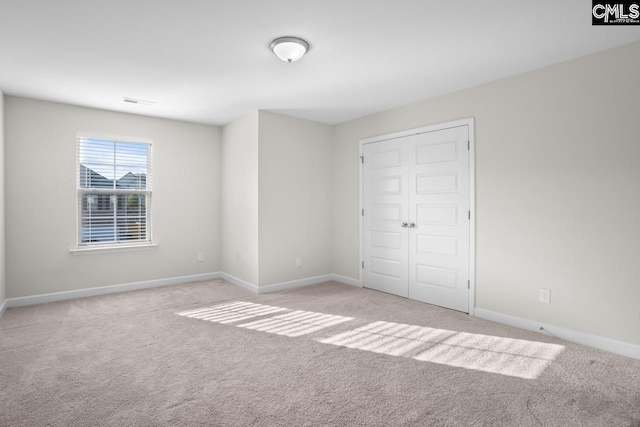 unfurnished bedroom with light colored carpet and a closet