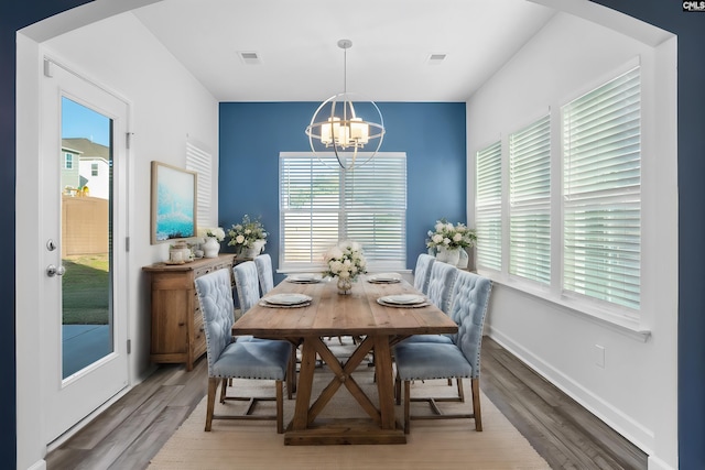 dining area featuring wood-type flooring and an inviting chandelier