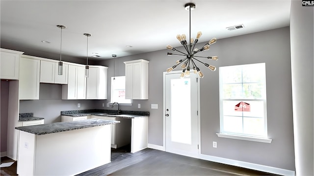 kitchen with sink, decorative light fixtures, white cabinetry, a notable chandelier, and a kitchen island