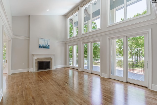 unfurnished living room with a high end fireplace, light wood-type flooring, and a high ceiling