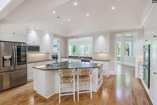 kitchen with white cabinetry, light hardwood / wood-style floors, appliances with stainless steel finishes, and a kitchen island