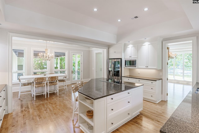 kitchen with a notable chandelier, white cabinets, light wood-type flooring, a kitchen island, and appliances with stainless steel finishes