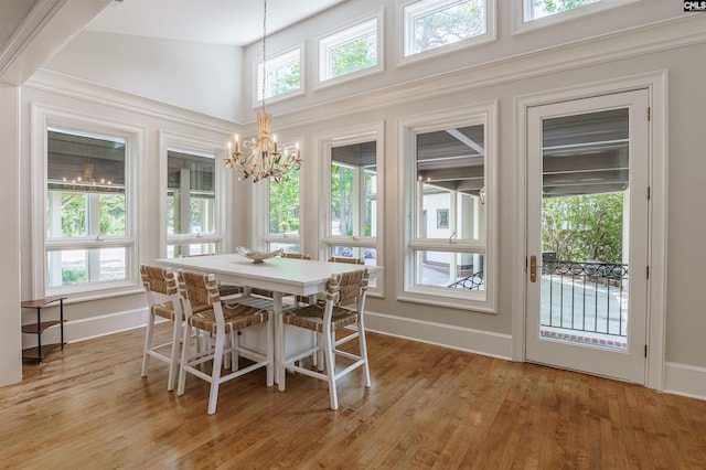 dining area featuring an inviting chandelier, hardwood / wood-style flooring, and high vaulted ceiling