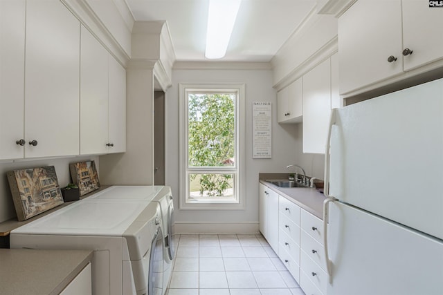 clothes washing area with cabinets, light tile patterned floors, washing machine and dryer, and sink