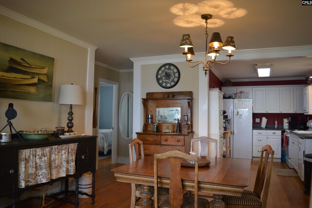 dining room with hardwood / wood-style flooring, a notable chandelier, and ornamental molding