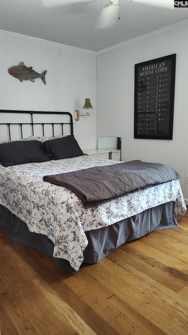 bedroom with a textured ceiling, ornamental molding, hardwood / wood-style floors, and ceiling fan