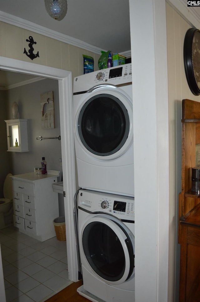 laundry room with stacked washer and clothes dryer, crown molding, and tile patterned flooring