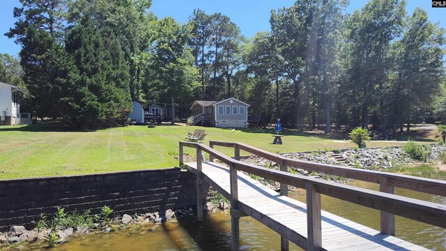 view of dock with a water view and a lawn