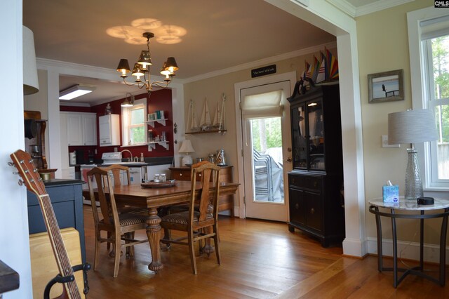 dining area featuring crown molding, wood-type flooring, and a notable chandelier