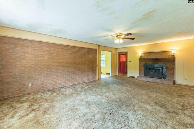 unfurnished living room featuring a ceiling fan, carpet flooring, a textured ceiling, and brick wall