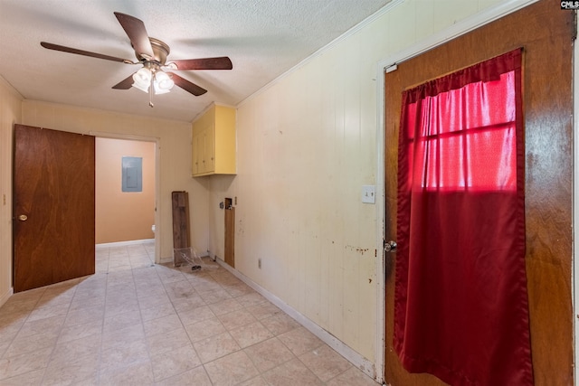 interior space with crown molding, a ceiling fan, a textured ceiling, electric panel, and baseboards