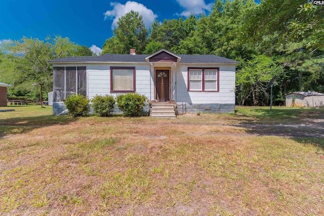 view of front of property featuring a chimney, crawl space, a front yard, and a sunroom