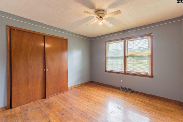 unfurnished bedroom with a textured ceiling, a closet, visible vents, and light wood-style floors