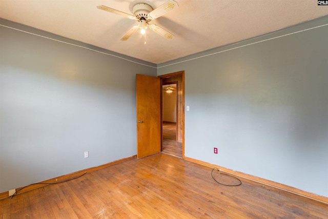 empty room with ceiling fan, light wood-type flooring, and baseboards