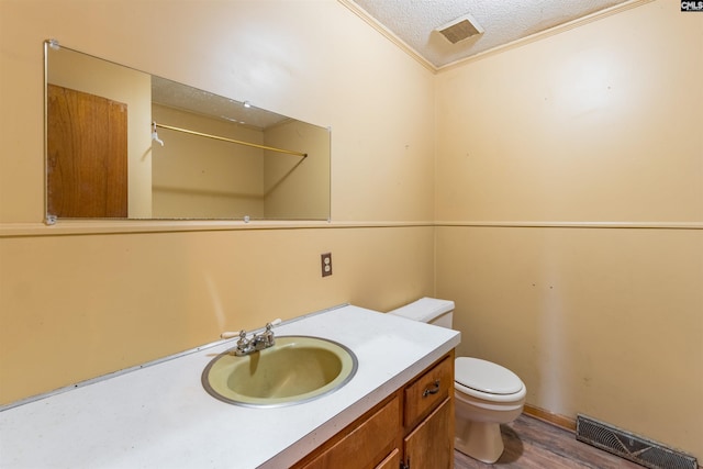 bathroom featuring visible vents, a textured ceiling, toilet, and vanity