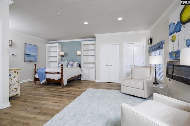 bedroom with wood-type flooring, crown molding, and multiple closets