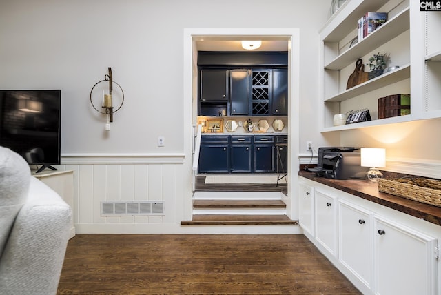 bar featuring dark hardwood / wood-style flooring, blue cabinetry, built in features, white cabinets, and butcher block counters