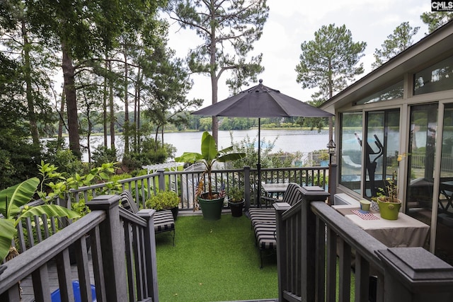 wooden deck with a water view and a lawn