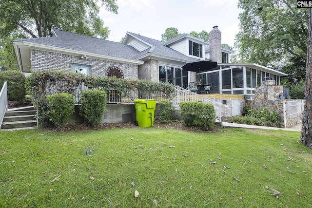 rear view of house with a sunroom and a lawn