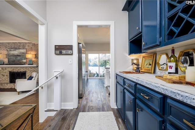 kitchen featuring a brick fireplace, brick wall, blue cabinets, sink, and dark hardwood / wood-style floors