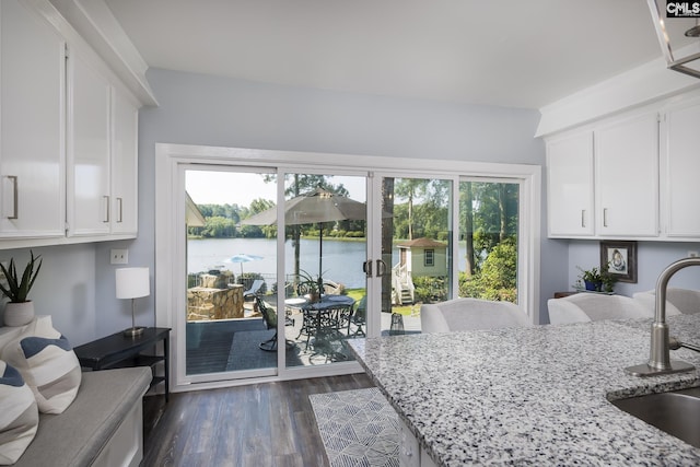 kitchen featuring light stone countertops, a water view, and white cabinetry