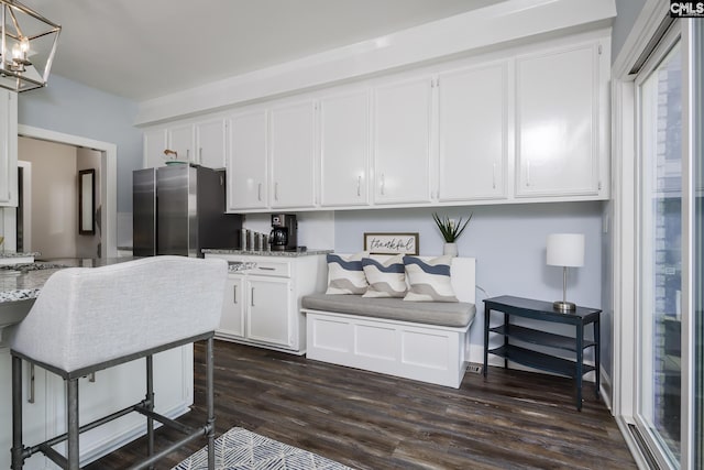 kitchen with white cabinets, stainless steel fridge, dark hardwood / wood-style flooring, and light stone counters