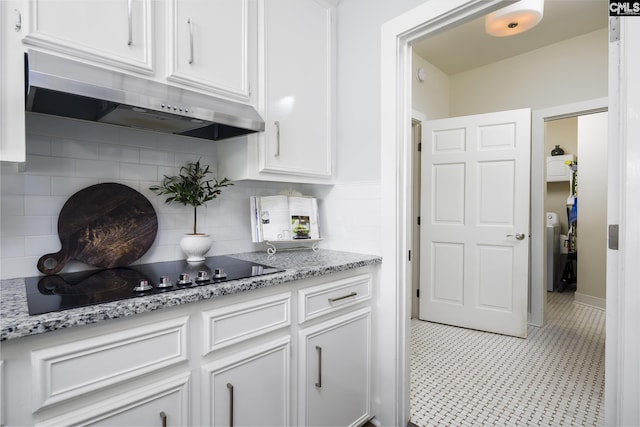 kitchen with white cabinets, light stone countertops, black electric cooktop, and backsplash