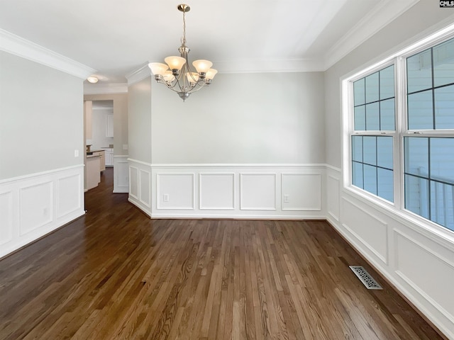 spare room with an inviting chandelier, crown molding, and dark hardwood / wood-style floors