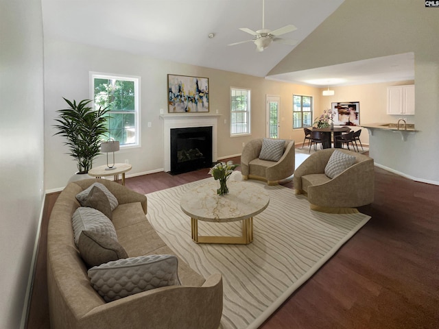 living area featuring a fireplace with flush hearth, a wealth of natural light, a ceiling fan, and wood finished floors