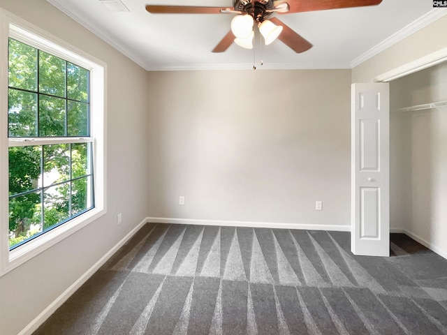 unfurnished bedroom featuring multiple windows, ceiling fan, crown molding, and dark colored carpet