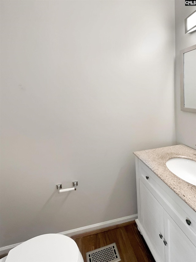 bathroom with toilet, wood-type flooring, and vanity