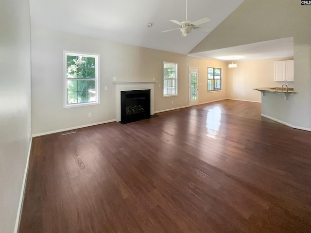 unfurnished living room featuring visible vents, dark wood-type flooring, a fireplace with flush hearth, a ceiling fan, and baseboards