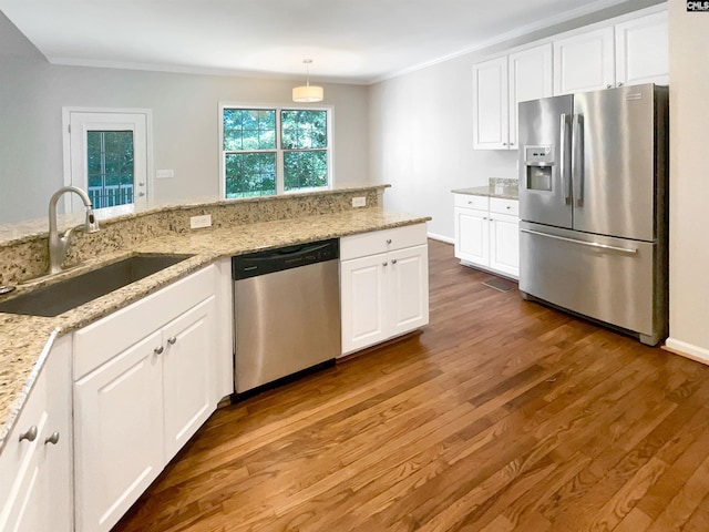 kitchen with appliances with stainless steel finishes, hanging light fixtures, white cabinetry, and sink