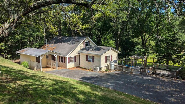 view of front of property featuring driveway, a wooden deck, and a front yard