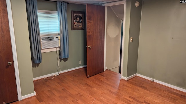 unfurnished bedroom featuring cooling unit, baseboards, and wood finished floors