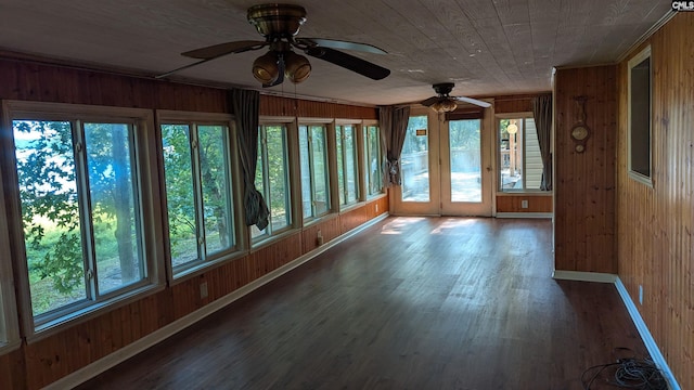 unfurnished sunroom featuring a ceiling fan, wooden ceiling, and plenty of natural light