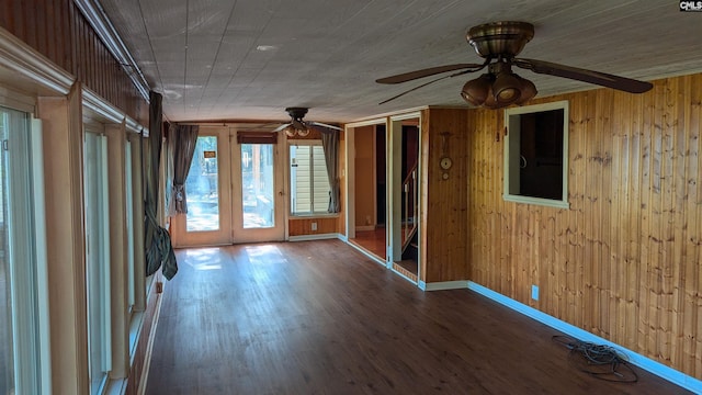 spare room featuring wood walls, baseboards, a ceiling fan, and wood finished floors