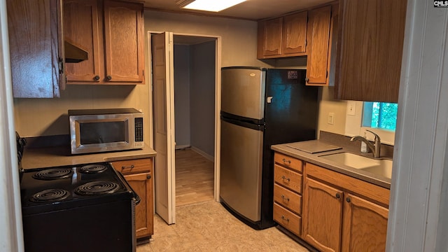 kitchen with stainless steel appliances, a sink, light countertops, and under cabinet range hood