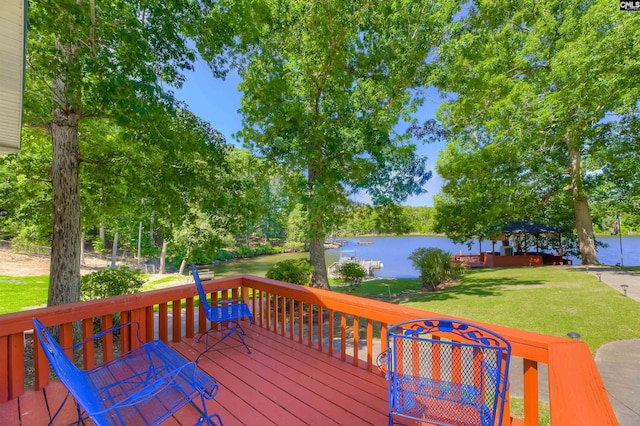 wooden terrace with a water view and a lawn