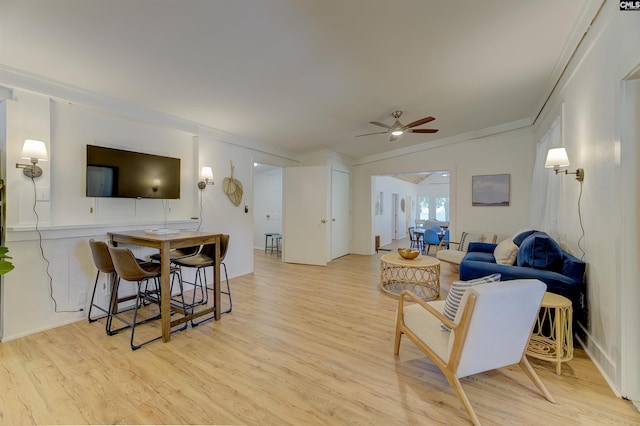 living room with light hardwood / wood-style floors, ornamental molding, and ceiling fan