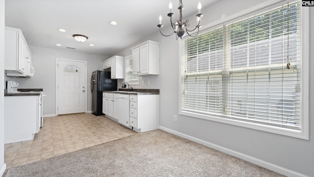 kitchen with white appliances, light colored carpet, sink, a notable chandelier, and white cabinets