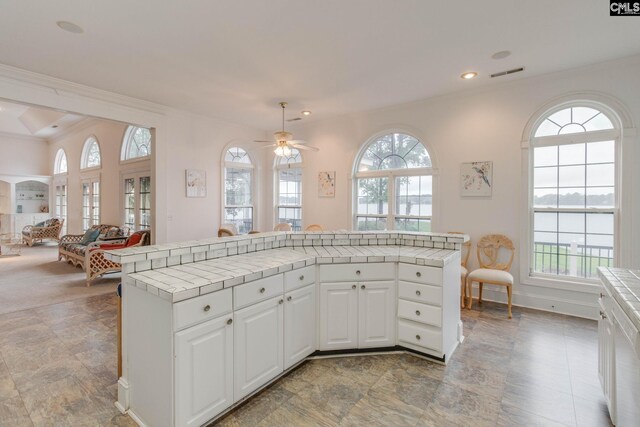 kitchen featuring light tile patterned flooring, white cabinetry, tile countertops, and a healthy amount of sunlight