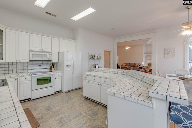 kitchen with a breakfast bar area, white cabinets, white appliances, light tile patterned floors, and ceiling fan