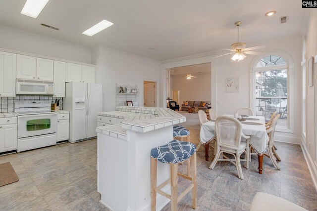 kitchen featuring light tile patterned flooring, tasteful backsplash, white appliances, ceiling fan, and tile countertops