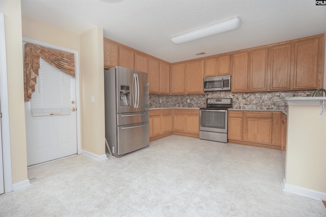 kitchen with tasteful backsplash, appliances with stainless steel finishes, and light tile patterned floors