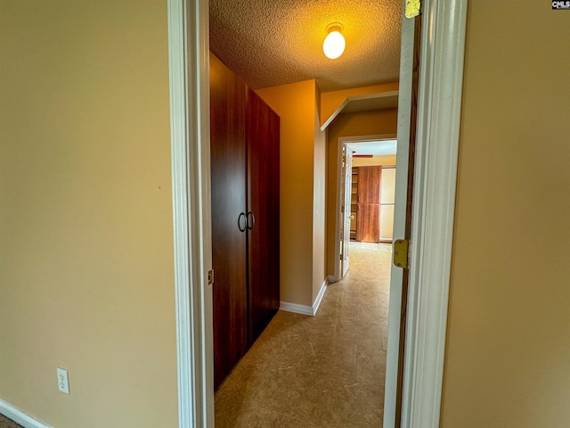 corridor with a textured ceiling and tile patterned flooring