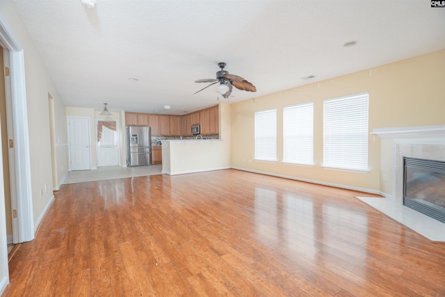 unfurnished living room featuring light hardwood / wood-style flooring and ceiling fan